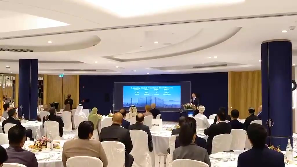 Seated guests facing the screen at a HONOR corporate event.