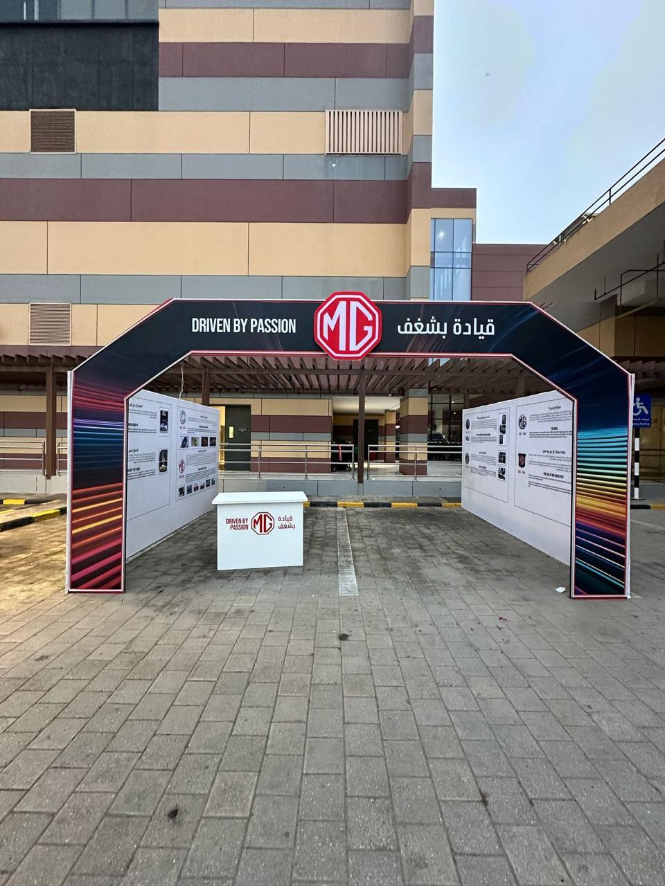 An MG-branded entrance arch and sign outside a venue.