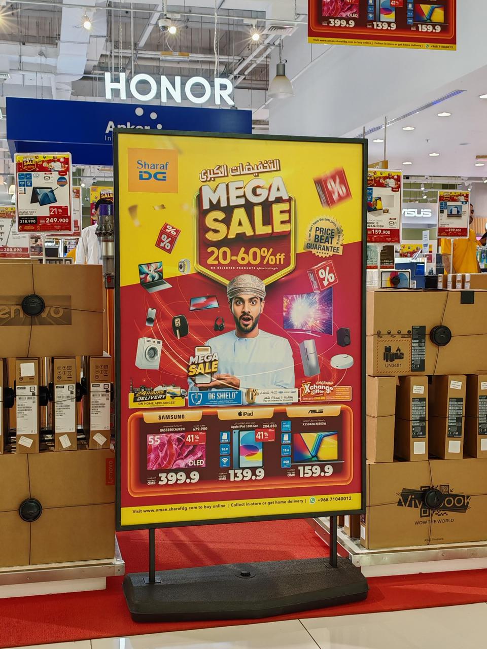 A freestanding printed promotion board inside an electronics store.